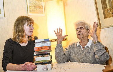 Foto: Junge Frau und ältere Frau mit Bücherstapel