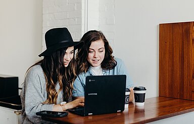 Foto: Zwei Frauen sitzen vor einem Laptop